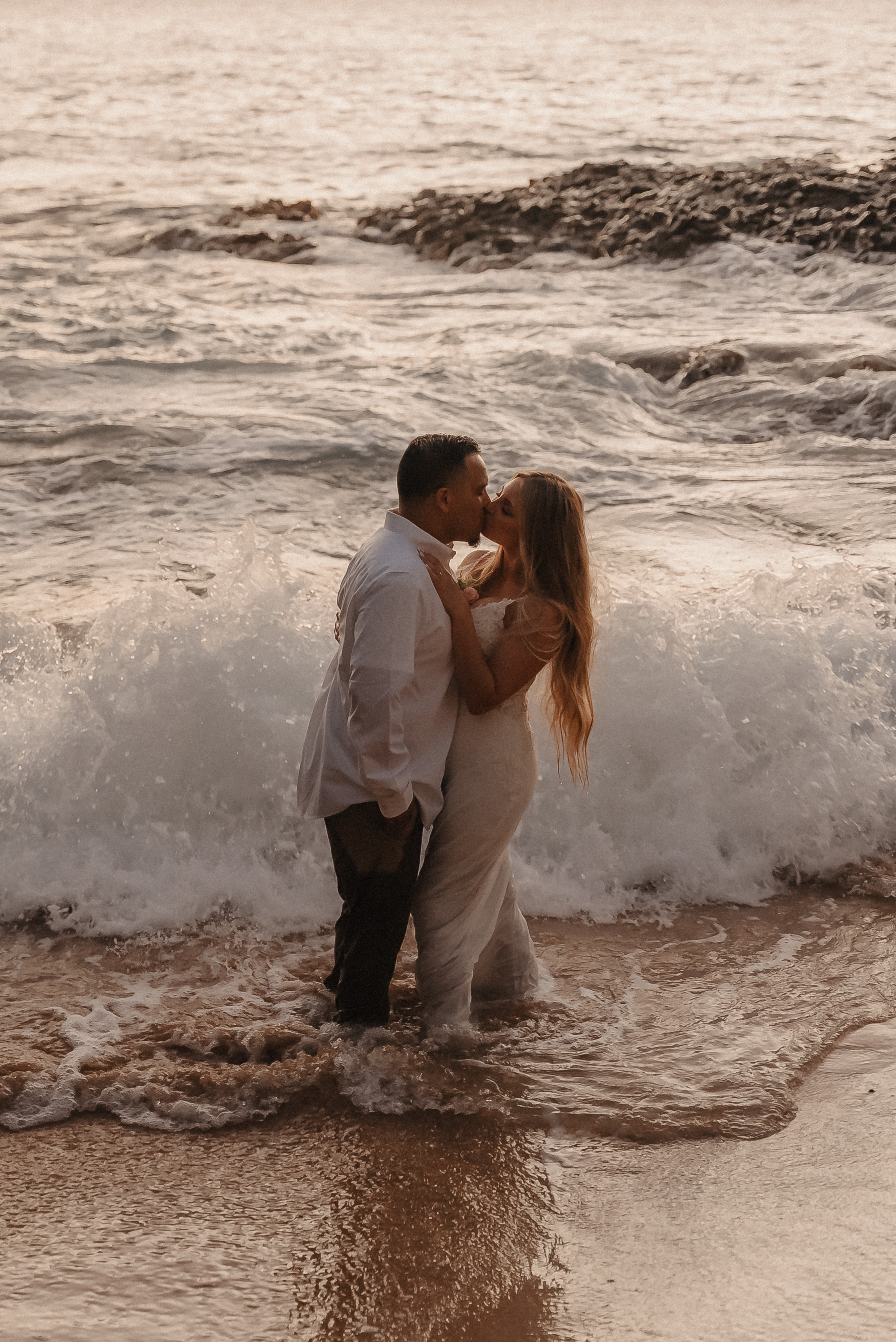 Couple kissing in the ocean waves at Villa Vedas, Tabanan