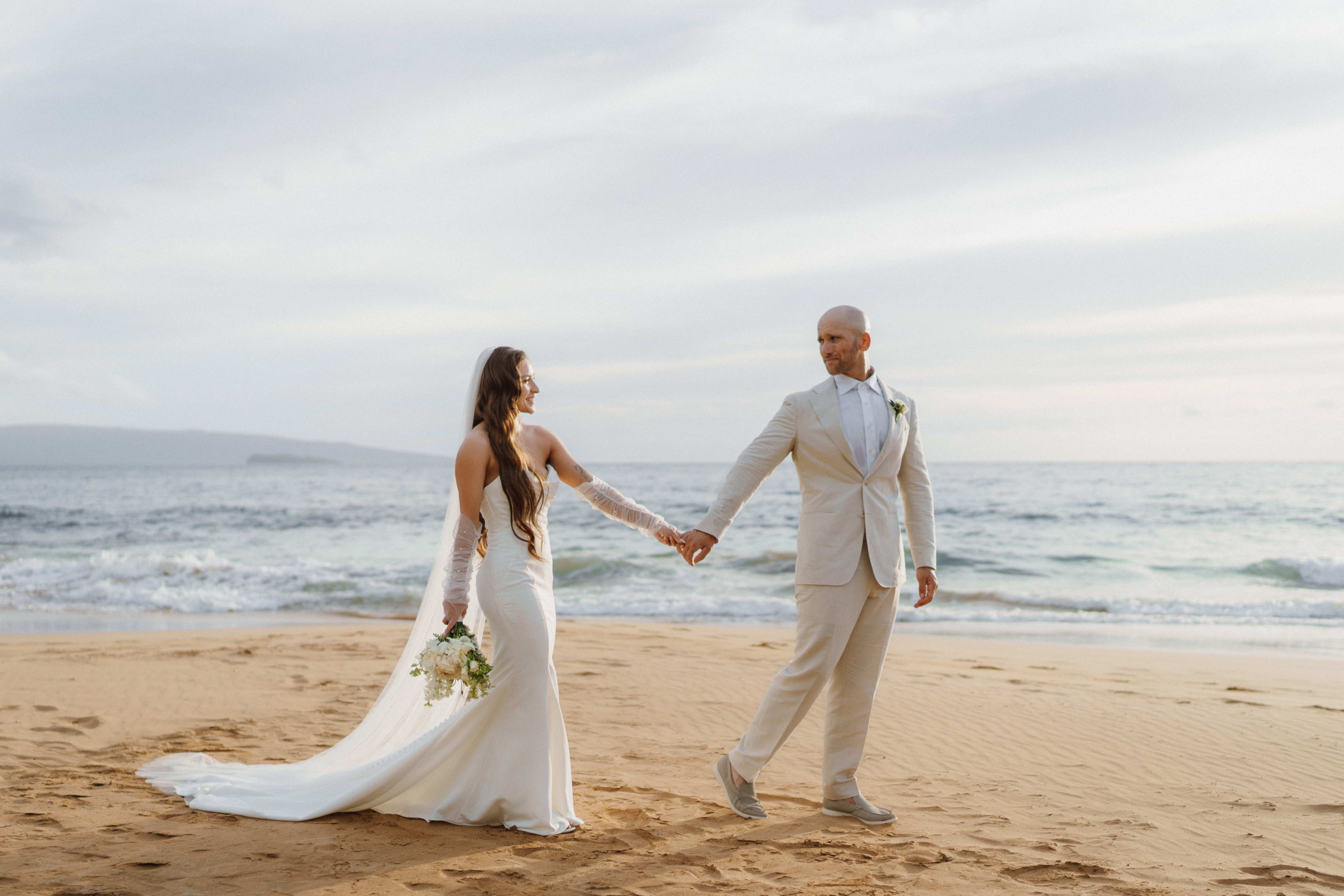 Bride and groom holding hands on the beach at The Royal Pita Maha, Ubud