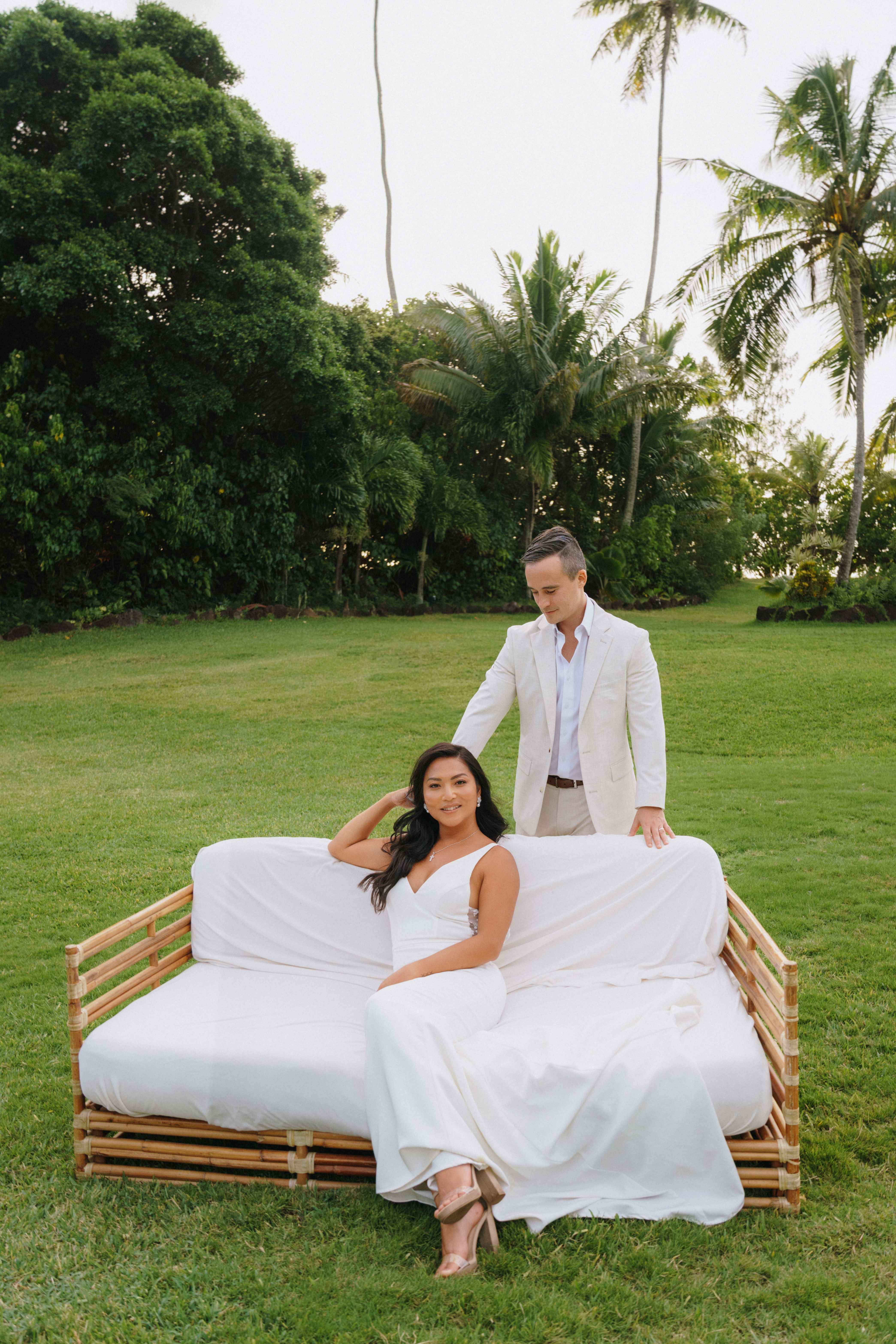Bride and groom on a bamboo daybed at a Bali garden wedding at sunset